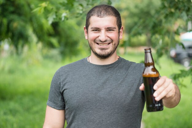 Homem alegre felicidades com garrafa para a câmera