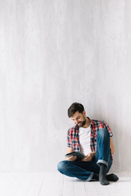 Foto grátis homem alegre usando tablet no chão