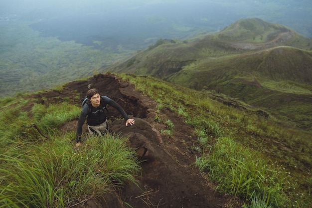 Homem alpinista escalando uma parede íngreme na montanha