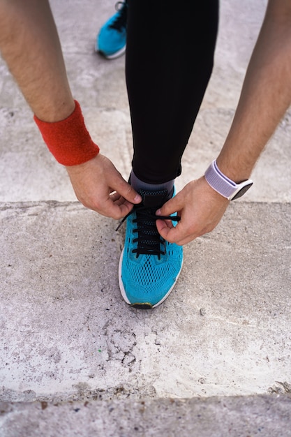 Foto grátis homem amarrando seus sapatos de desporto em fundo de concreto