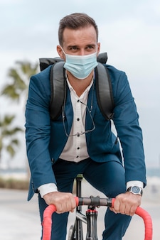 Homem andando de bicicleta com máscara médica