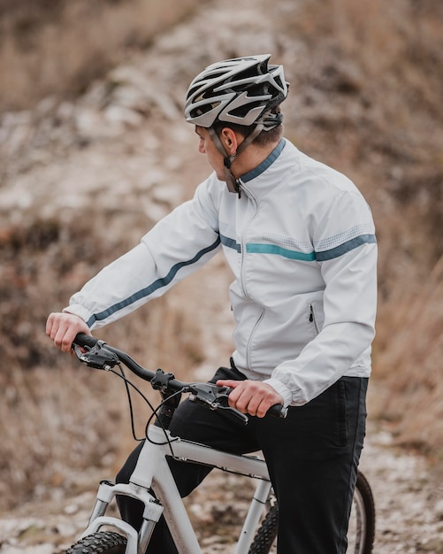 Homem andando de bicicleta em um dia frio e olhando para longe