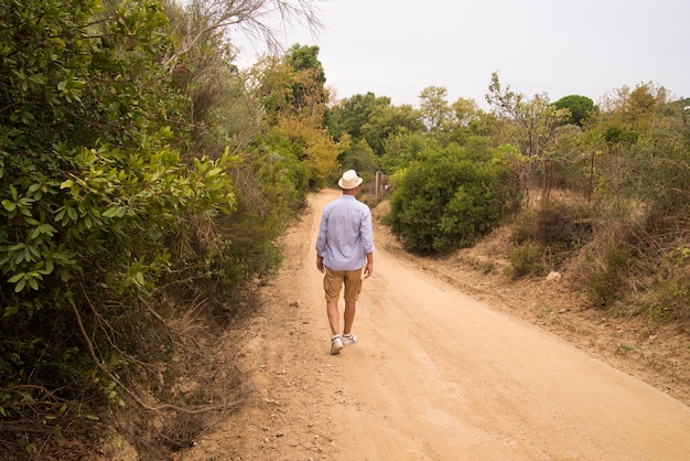 Homem andando na estrada com humor relaxado.