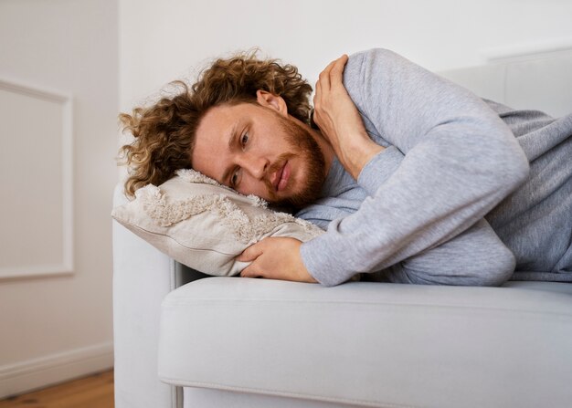 Homem ansioso deitado no sofá plano médio