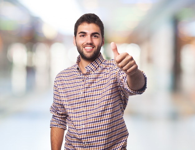 Homem apontando o polegar para cima sorrindo.