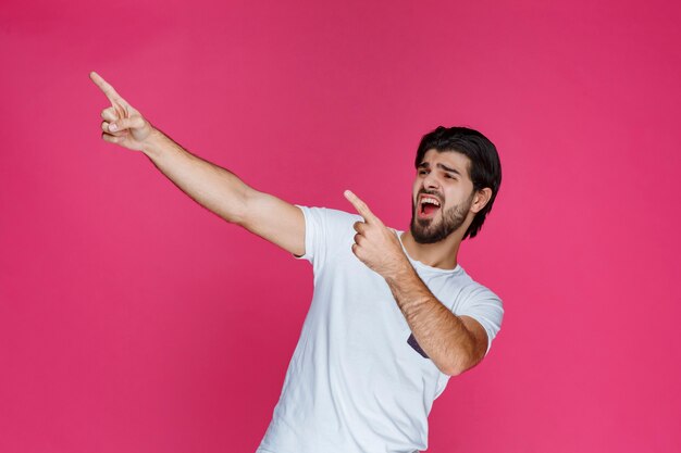 Homem apontando para alguém ou algo à esquerda.