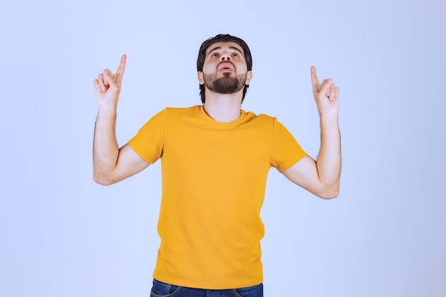 Foto grátis homem apontando para cima e demonstrando algo.