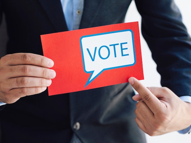 Homem apontando para uma cédula com uma mensagem de votação