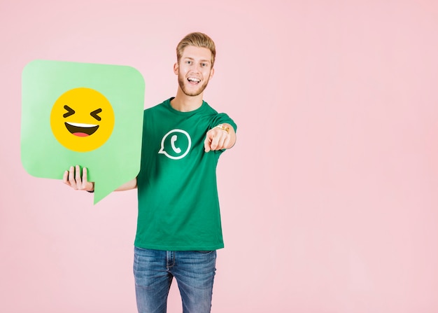 Foto grátis homem, apontar, seu, dedo, enquanto, segurando, fala, bolha, com, sorrindo, emoji