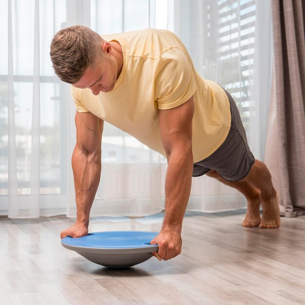 Homem apto a usar bola bosu para fazer exercício em casa