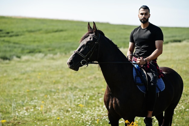 Homem árabe de barba alta usa cavalo árabe de passeio preto