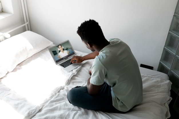 Homem armado com laptop na cama