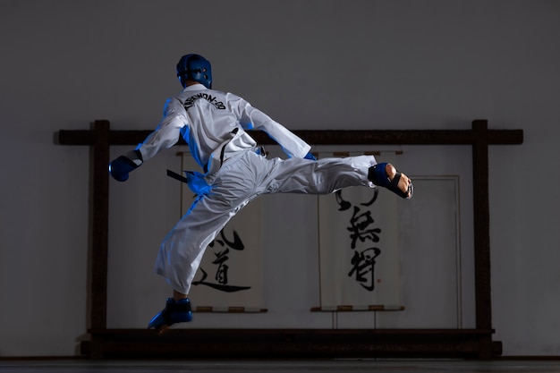 Homem asiático de tiro completo praticando taekwondo