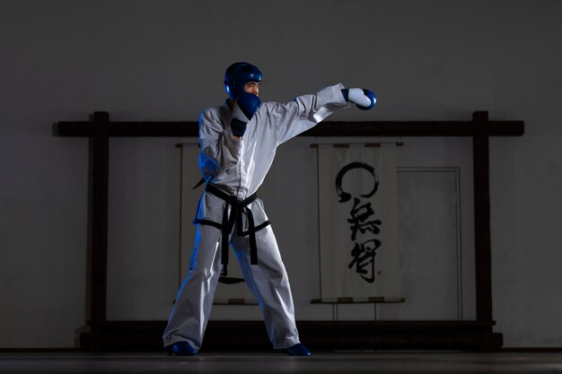 Homem asiático de tiro completo praticando taekwondo