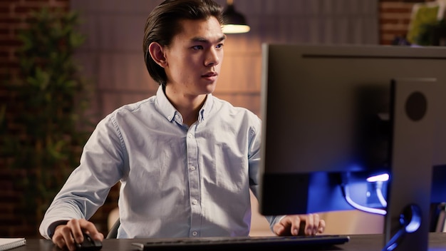 Homem asiático focado trabalhando em relatório comercial no site, usando computador para criar solução e plano econômico. Fazendo papelada e escrevendo e-mail para negócios de inicialização executiva.