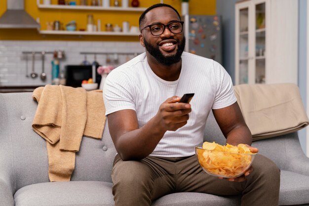 Homem assistindo tv e comendo batatinhas