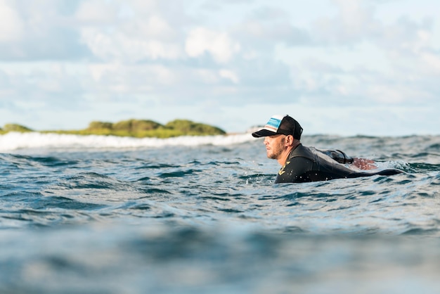 Homem ativo com equipamento especial permanecendo em uma prancha de surfe