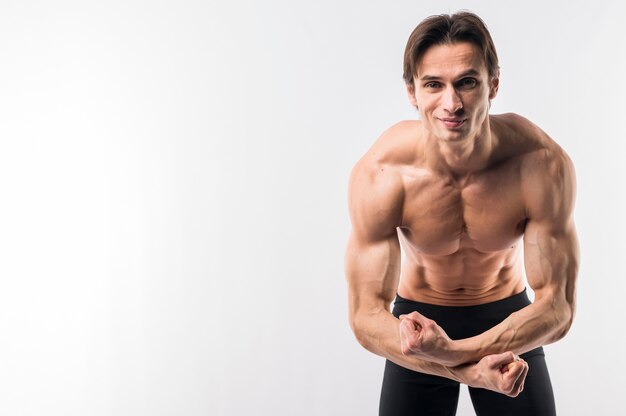 Homem atlético sem camisa, mostrando os braços muscly com espaço de cópia