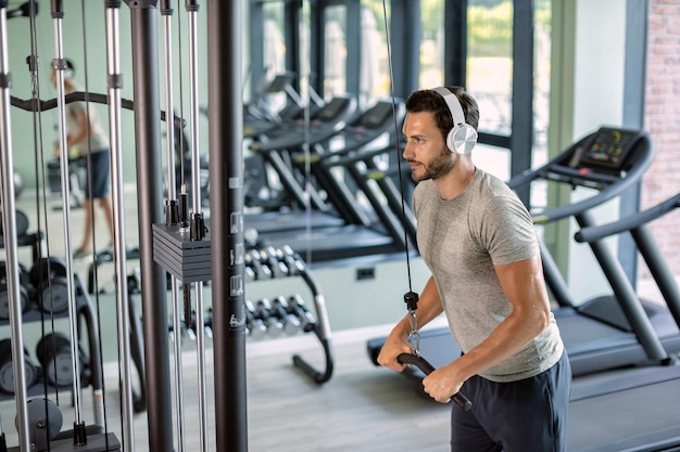 Homem atlético suado malhando na máquina de exercícios no health club