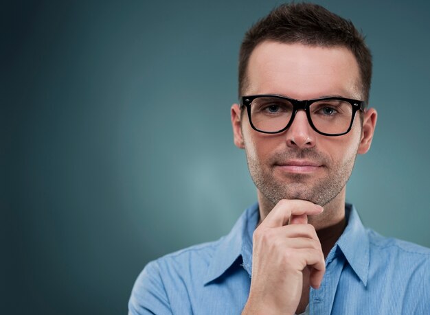 Homem atraente de óculos e mão no queixo