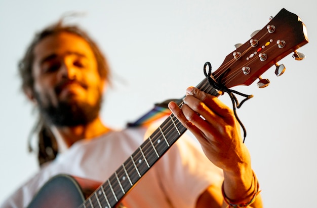 Homem baixo ângulo, tocando violão