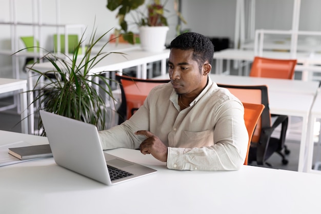 Homem baleado médio no trabalho com laptop