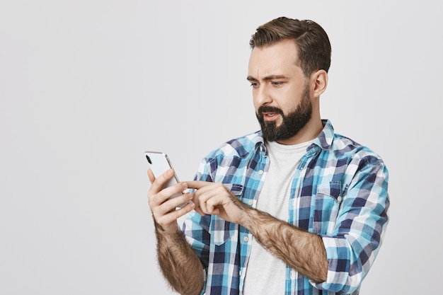 Homem barbudo adulto fazendo pedidos on-line usando o telefone celular