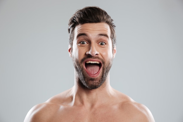 Homem barbudo animado com ombros nus e boca aberta
