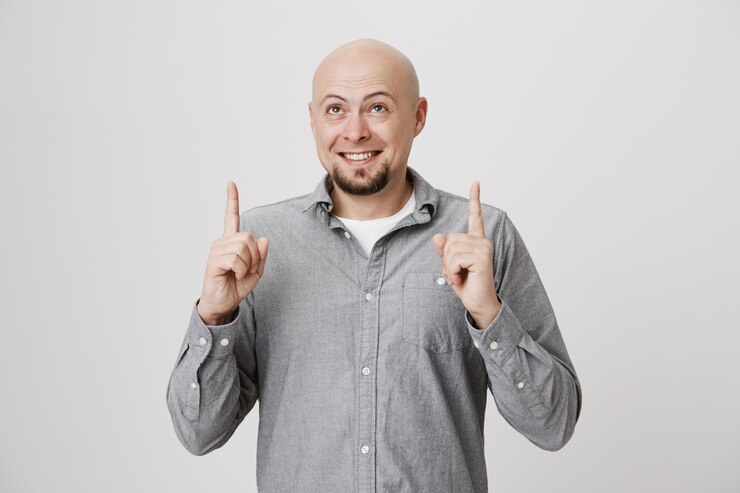 Foto grátis homem barbudo careca sorridente apontando e olhando para cima