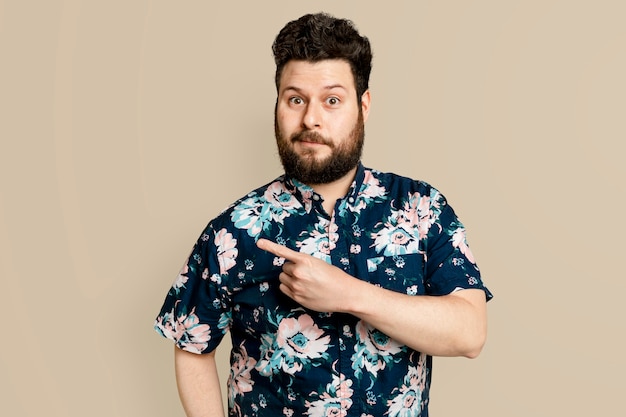 Homem barbudo com camisa floral de verão apontando para o lado