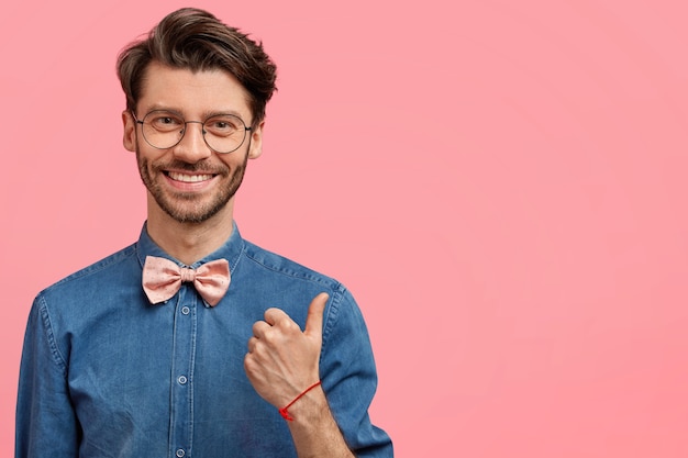 Homem barbudo com camisa jeans e gravata borboleta rosa