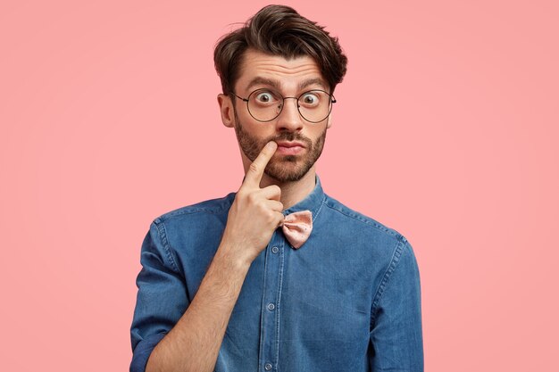 Homem barbudo com camisa jeans e gravata borboleta rosa