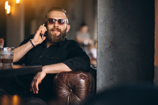 Homem barbudo com telefone sentado em um café