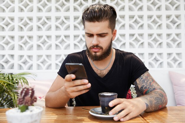 Homem barbudo elegante sentado em um café