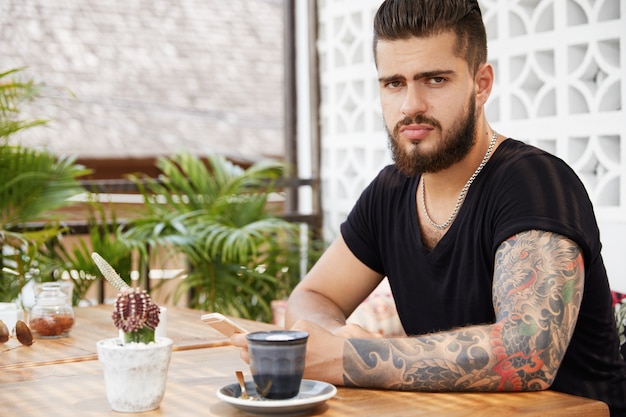 Homem barbudo elegante sentado em um café