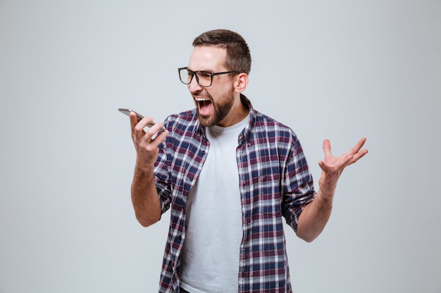 Homem barbudo em óculos, gritando no telefone