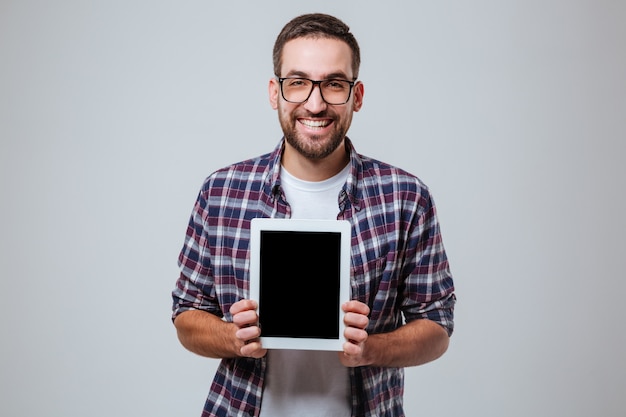 Homem barbudo em óculos mostrando a tela do computador tablet em branco