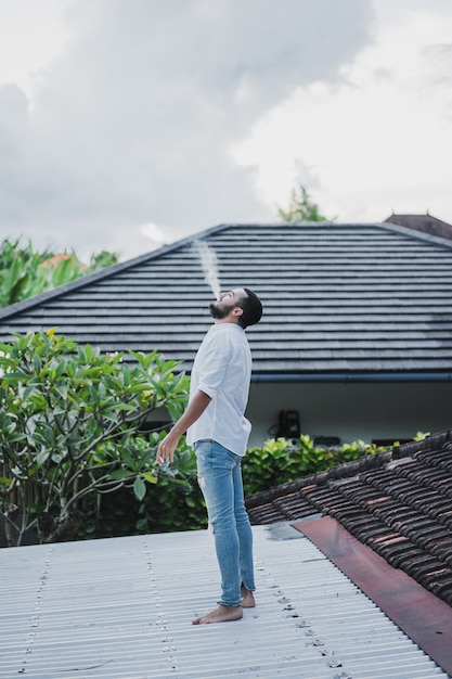 Homem barbudo fumando no telhado