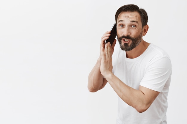 Homem barbudo maduro posando com seu telefone