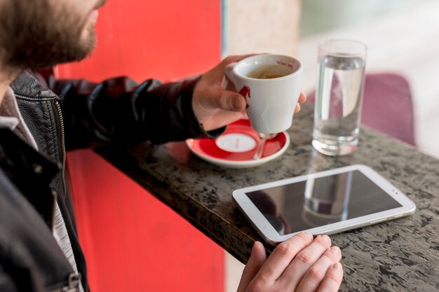 Homem barbudo segurando a taça perto de tablet