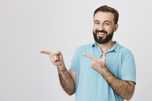 Homem barbudo sorridente e amigável apontando o dedo para a esquerda