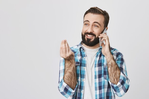 Homem barbudo sorridente e feliz explicando algo pelo celular, conversar