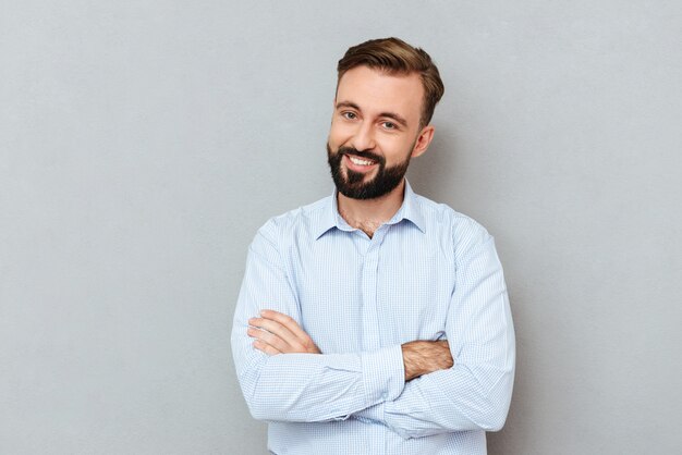 Homem barbudo sorridente em roupas de negócios com os braços cruzados