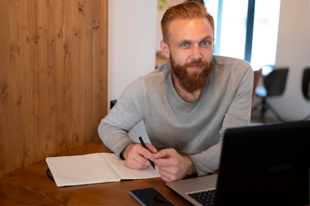 Foto grátis homem barbudo trabalhando em seu laptop