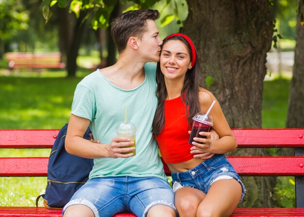 Homem, beijando, dela, namorada, segurando, smoothies, em, copo plástico