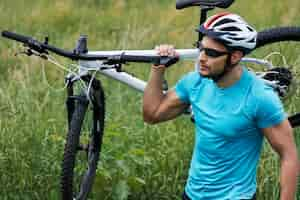 Foto grátis homem bem construído carregando sua bicicleta