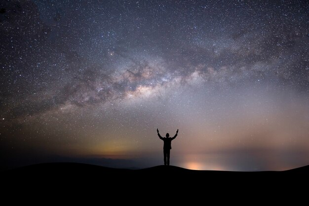 Homem bem sucedido silhueta no topo da colina em um fundo com estrelas