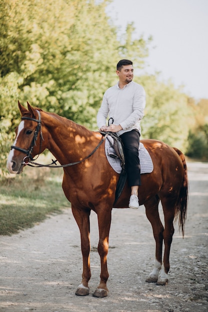 Homem bonito andando a cavalo na floresta