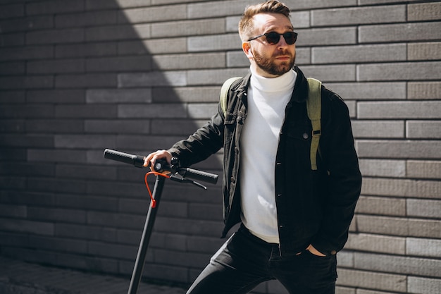 Homem bonito andando na cidade de scooter