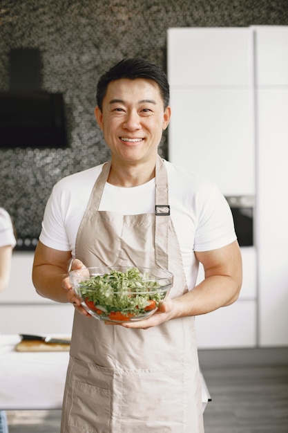 Homem bonito asiático cozinhando em casa.